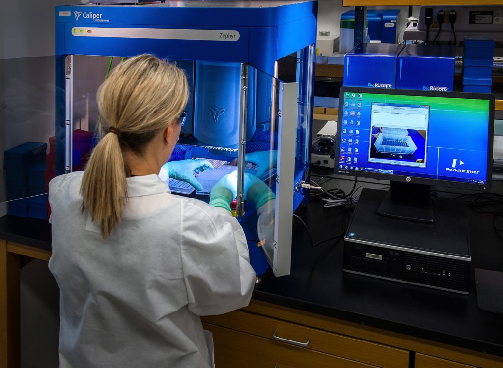 Healthcare worker uses a machine to analyze specimens.