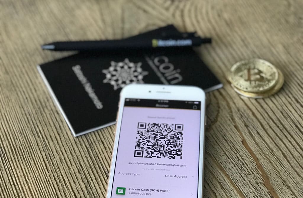 Image shows a Bitcoin and a phone with a digital wallet for transactions.