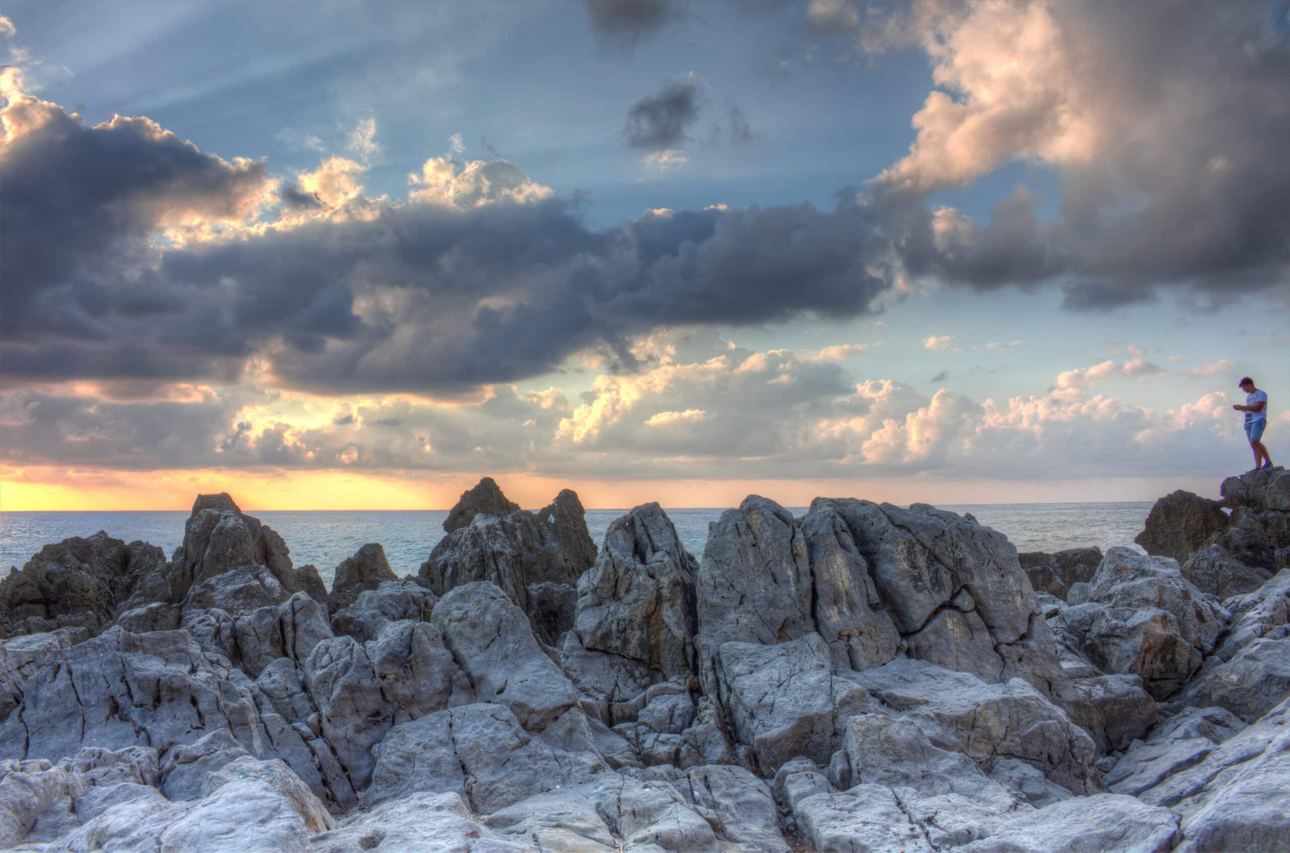 Image of beautiful cloudy sky against coastal rocks, and a traveler who backs up his photos to the cloud.